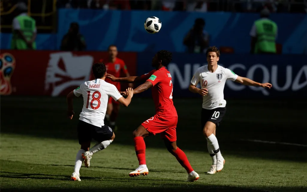 世界杯淘汰赛氛围：球员在高强度对抗中逼抢与争顶，体育摄影风格